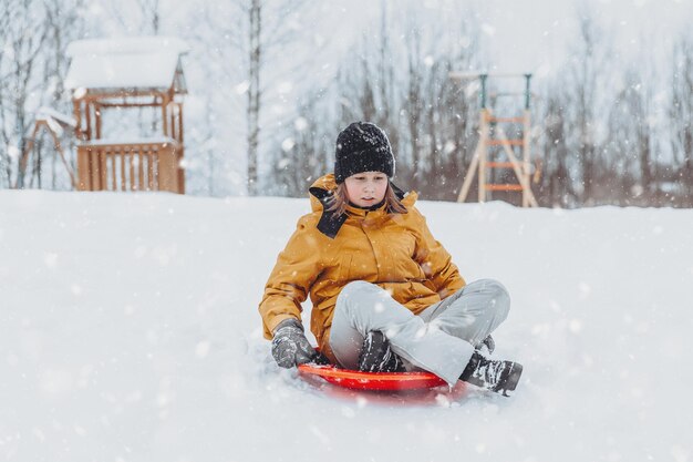 A girl rides down a slide in a winter park a healthy lifestyle a sports walk