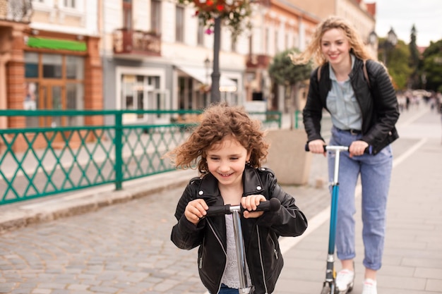 The girl rides a scooter for the first time together with her mom