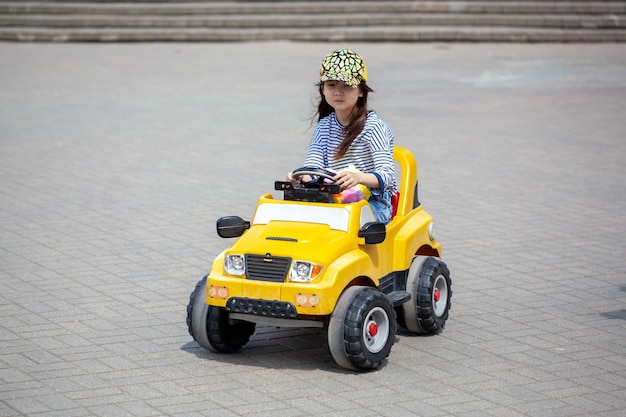 Girl rides on toy electric car in the Park in summer day