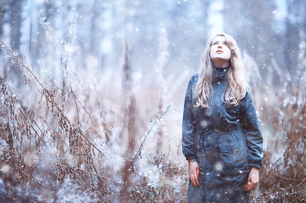 girl romantic portrait first snow autumn, snowflakes blurred background seasonal winter