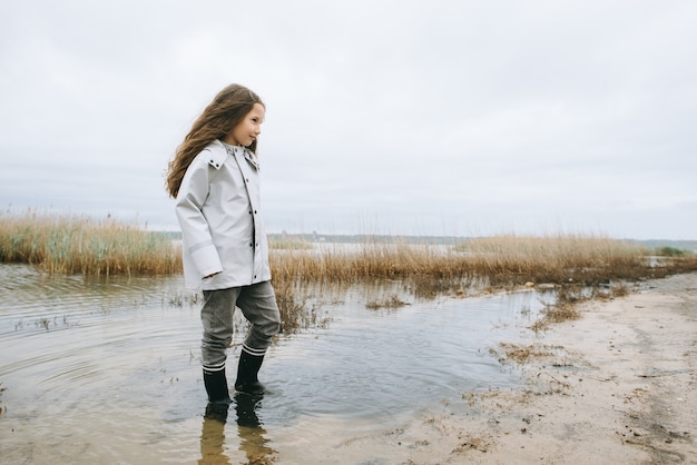 girl in rubber boots have a fun near the lake