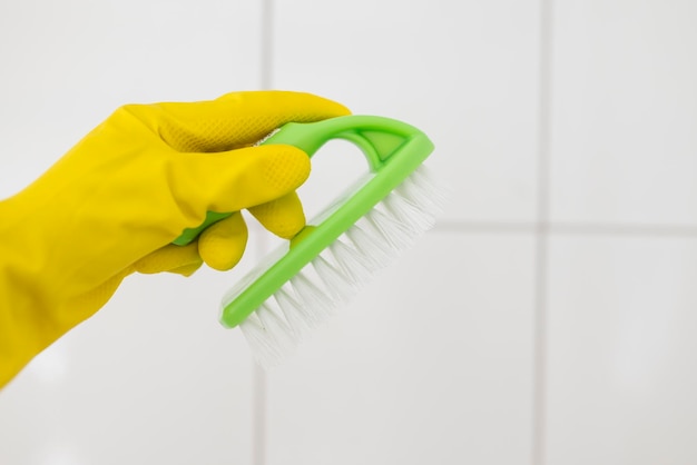 girl in rubber gloves with a brush does cleaning in the bathroom