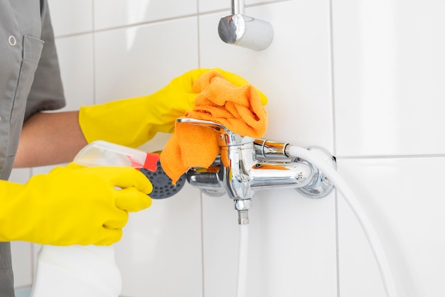 a girl in rubber gloves with a sponge does cleaning in the shower bathroom