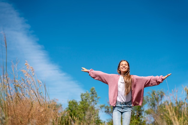 The girl runs with her arms open in the form of an airplane. Fresh air, raised hands to the blue sky