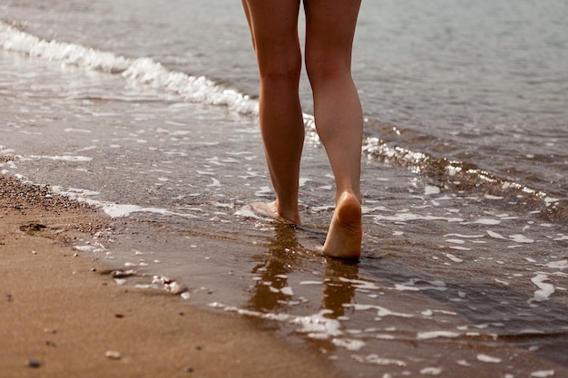 Photo a girl's feet walking on the sand along the sea coast. sand and sea water. the girl walks on the sand. stop close-up.