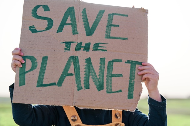 Girl's hand holding a cardboard sign that says SAVE THE PLANET