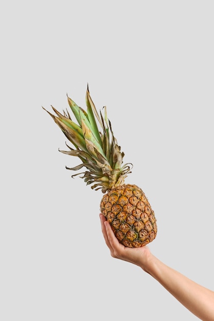 Girl's hand holds a ripe pineapple Creative pineapple layout Flat lay healthy eating concept Ripe seasonal produce from the local farmers market