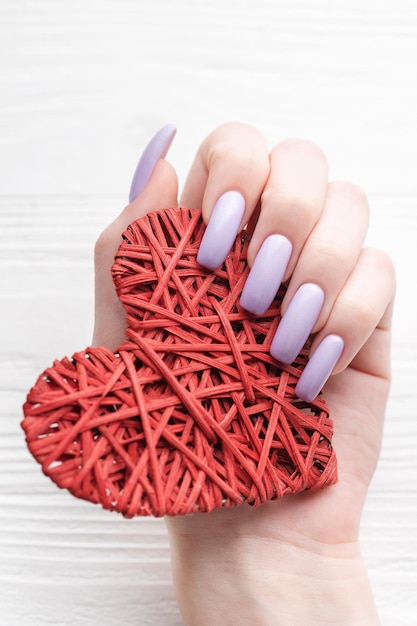 Girl's hands with delicate purple manicure and decoratine heart