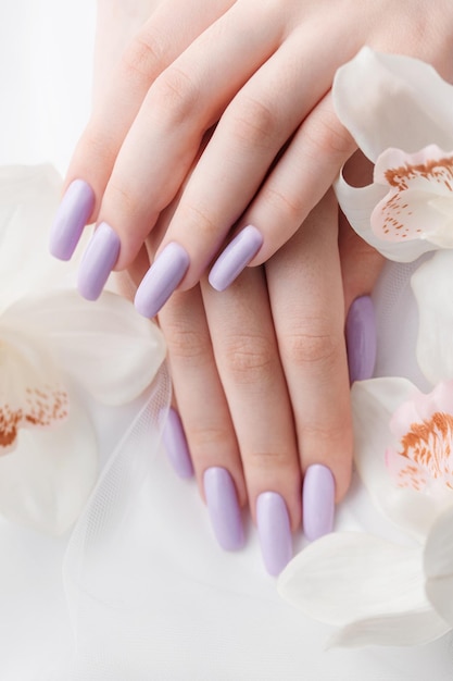 Girl's hands with delicate purple manicure and orchid flowers