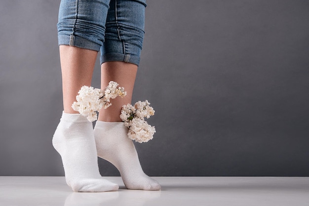 Girl's legs in socks in which lilac flowers are inserted concept female health veins and legs