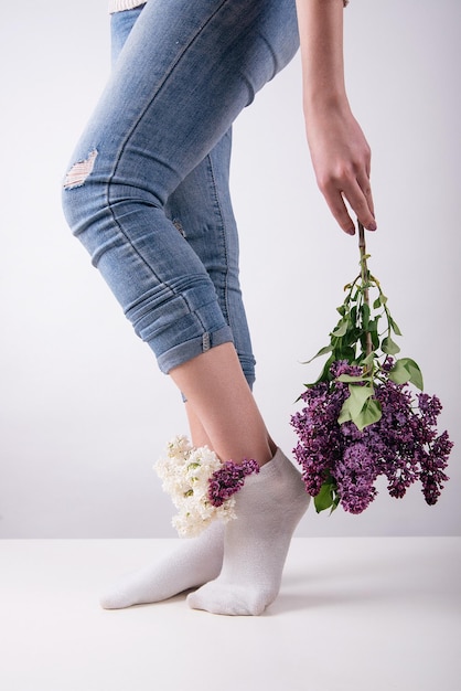 Girl's legs in socks in which lilac flowers are inserted concept female health veins and legs