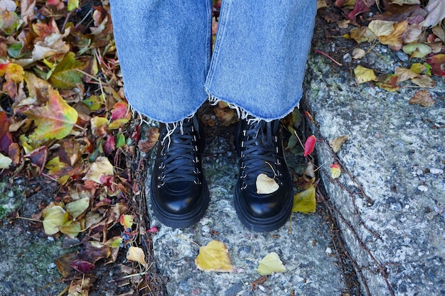 Girl's legs on the stairs in the autumn park in black boots top view Autumn concept