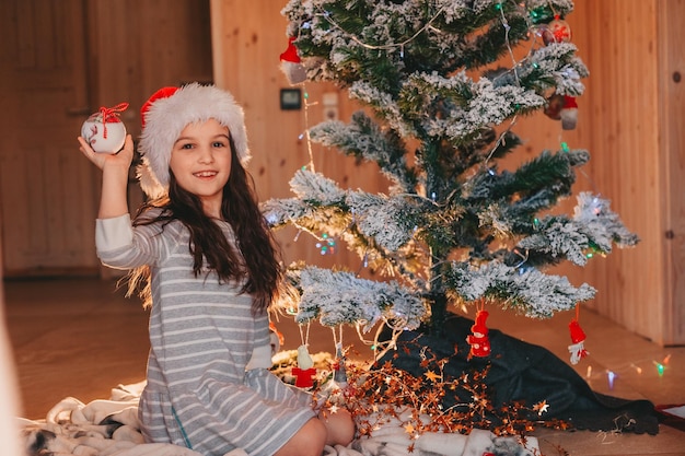 a girl in santas hat playing with christmas toys at home