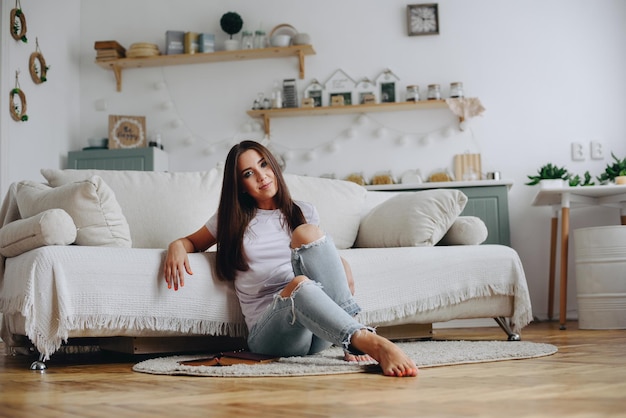 The girl sat down on the carpet to rest The girl is sitting at home near the sofa Home furnishings