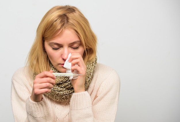 Girl in scarf hold thermometer and tissue close up Cold and flu remedies High temperature concept Take temperature and assess symptoms Measure temperature Woman feels badly ill sneezing