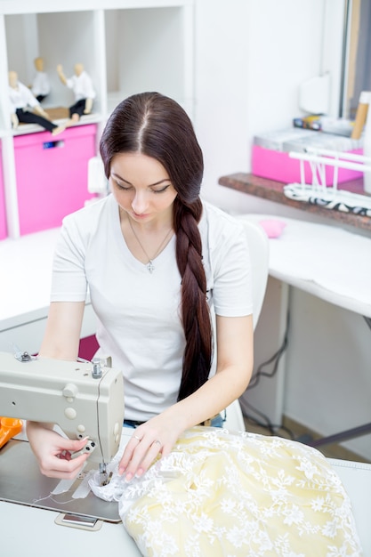 Girl seamstress sew on the sewing machine