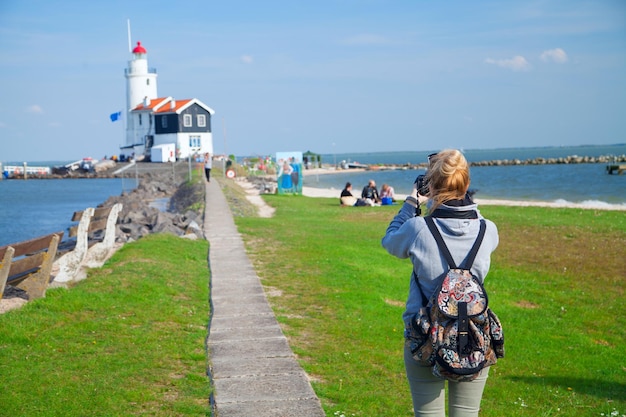 Girl shoots video at the lighthouse on the sea