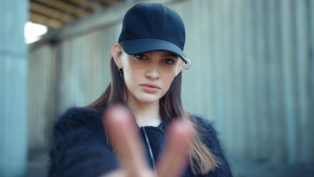 Girl showing v sign at camera on street Woman showing peace sign with fingers