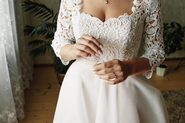 A girl in a silk robe sits on a chair and crosses her hands on her knees.