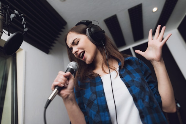 The girl sings her song in a modern recording studio 