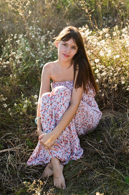 Girl sit at dry grass meadow in romantic maxi dress