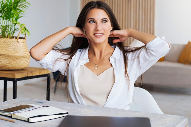 Girl sits at desk in home office and shows joyful gesture with her hands.