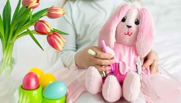 A girl sits in front of a easter bunny with a basket of easter eggs.