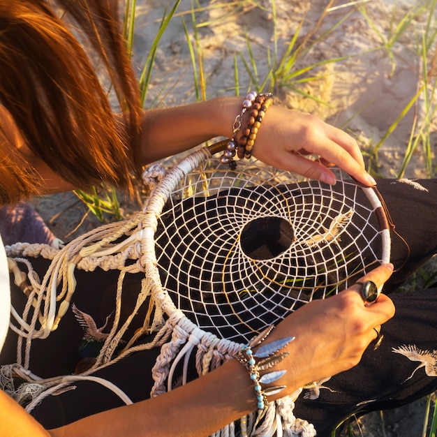 A girl sits on the grass and holds a dream catcher 