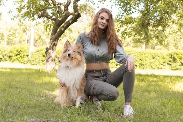 Girl sits on the grass with her beloved dog