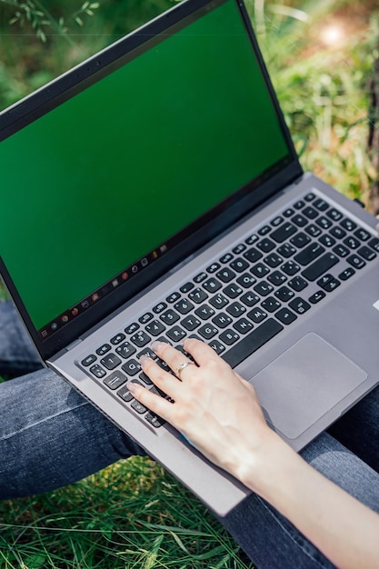 Girl sits on the grass and works at a laptop freelance selfeducation the concept of distance learning outdoors