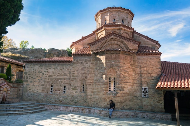 A girl sits near the Orthodox Greek church of the monastery Great Meteoron in Meteora Kalabaka Greece