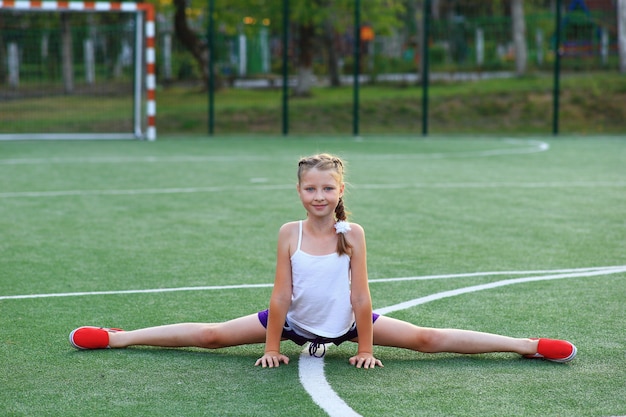 The girl sits on the twine on the sports ground.