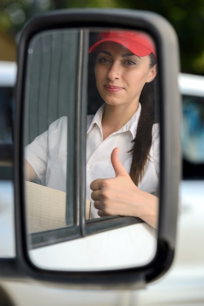 Girl sits behind the wheel and shows thumbs up.