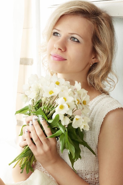 Girl sits on the window and holds the bouquet