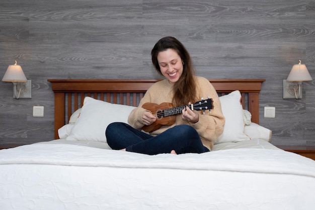 Girl sitting on the bed playing the guitar