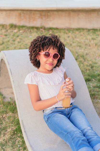 Girl sitting on a bench in the park drinking juice