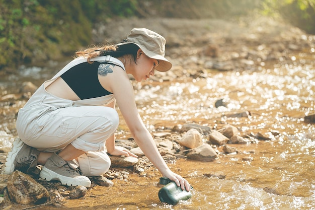 Girl sitting by the stream drinking water