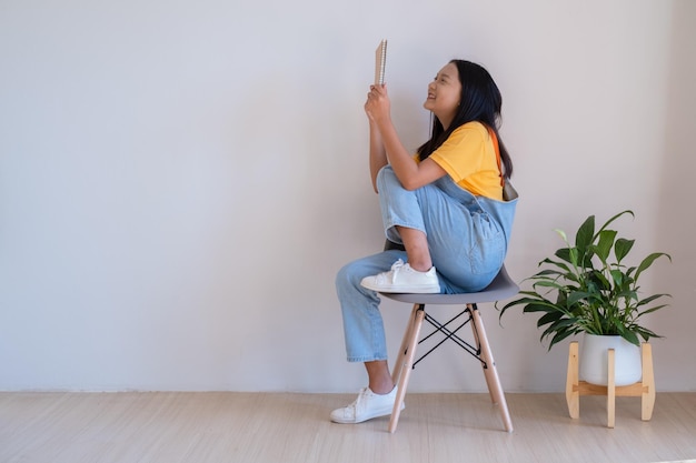 The girl sitting on a chair holding a book in a minimal room