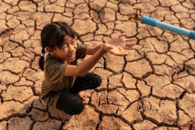 A girl sitting on dry ground Water crisis Concept hope and droughtxA