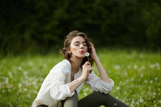 girl sitting in a field on the spring grass with dandelion flowers