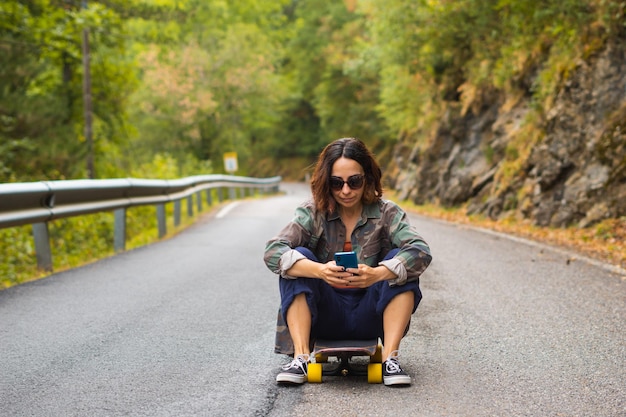 Girl sitting on skateboard using her phone