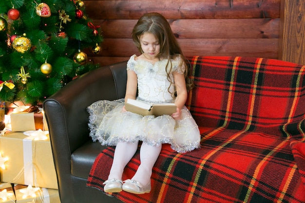 Girl sitting on a sofa with a book in her hands.