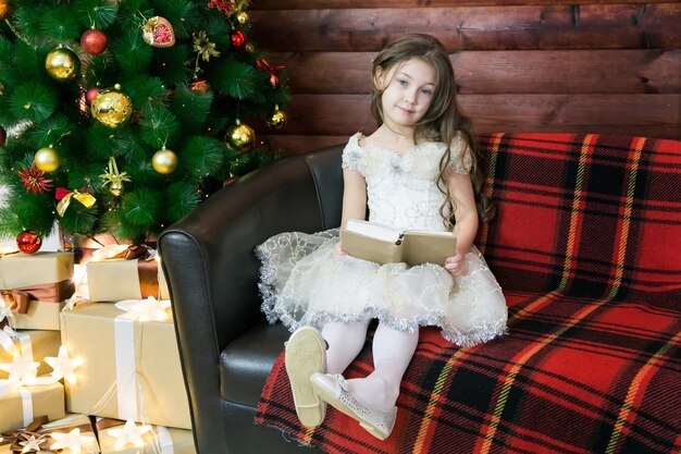 Girl sitting on a sofa with a book in her hands.