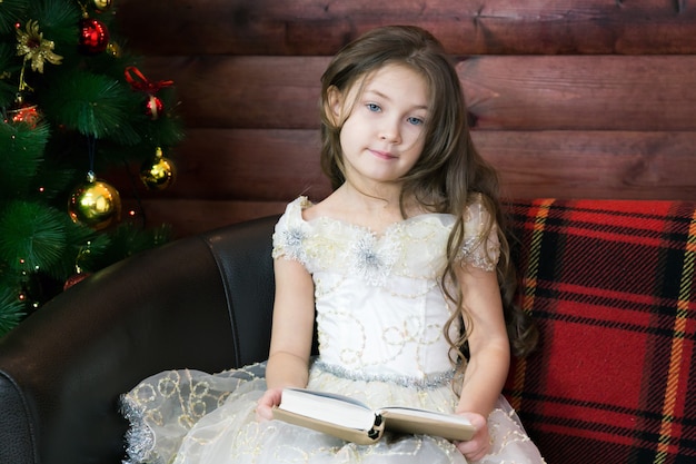 Girl sitting on a sofa with a book in her hands.