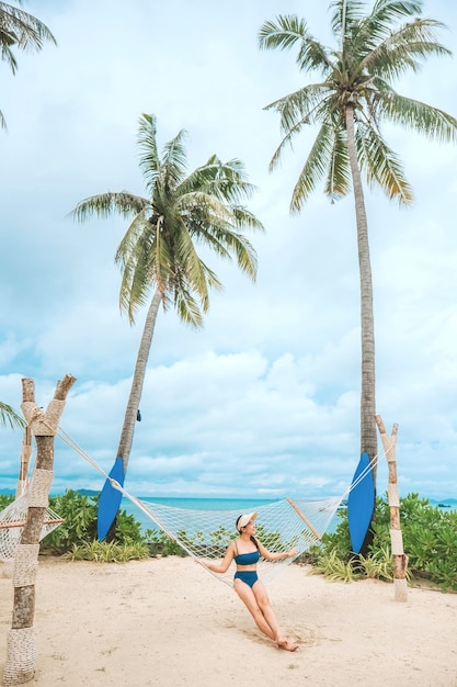 Girl sitting on a swing on white sand beach Near the coconut tree beautiful view at Phi Phi Thai