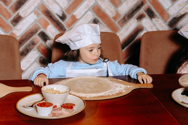 A girl sitting at a table with a pizza cutter and a plate of food on it.