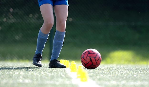 Photo girl skillfully dribbles ball between flip cups during football practice closeup shot