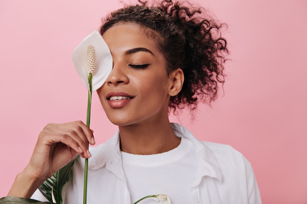 Girl smiles and covers her face with white flower