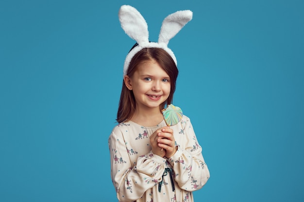 Girl smiling and holding a cookie in shape of heart wearing bunny ears