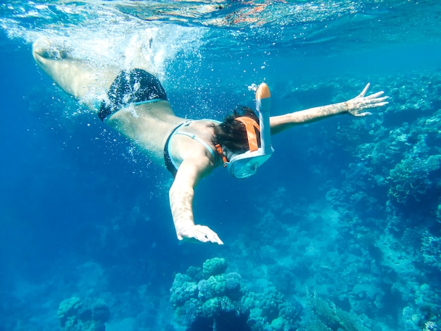 Girl snorkler swims underwater in the sea